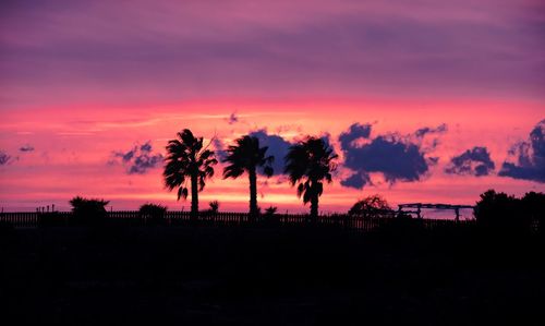 Silhouette trees on field against romantic sky at sunset