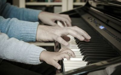 Cropped hands playing piano in home