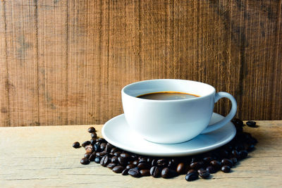 Close-up of coffee cup with beans on table