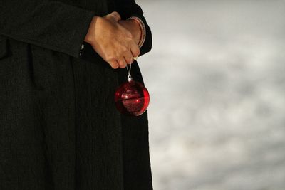 Close-up midsection of person holding red bauble