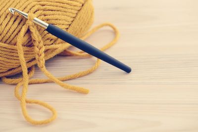 Close-up of knitting needle and wool on wooden table