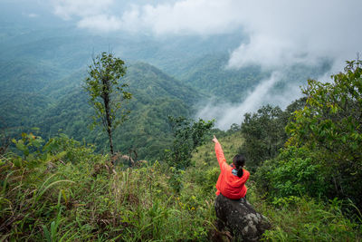 High angle view of woman sitting on rock against mountains