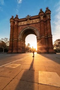 Triumphal arch on city street against sky during sunset