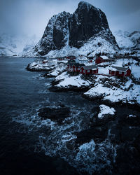 Snow covered building and mountains against sky