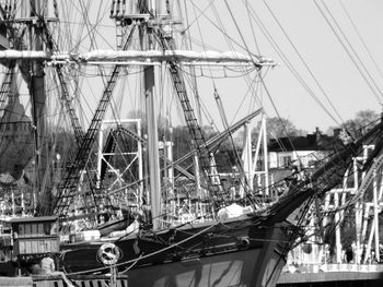 Sailboats moored at harbor against sky