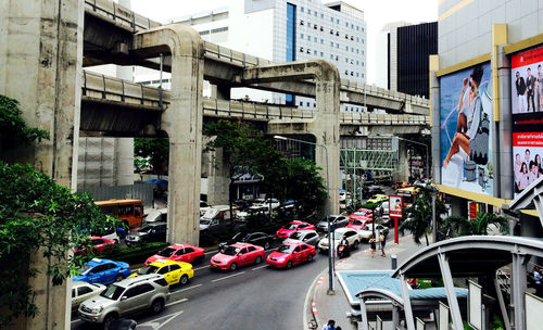 Cars on road by bridge in city against sky