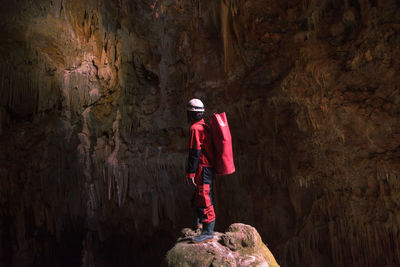 Side view of man standing on rock in cave