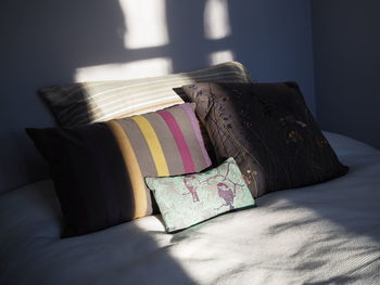 Close-up of decorative pillows on bed at home and sunlight