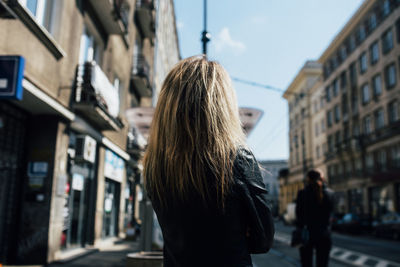 Rear view of woman standing on street in city