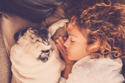 Directly above shot of woman sleeping with dog on bed