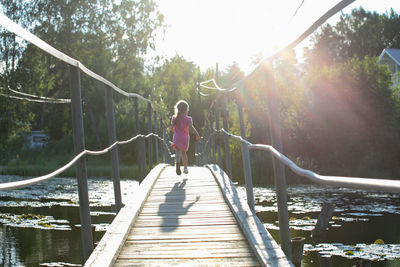 Rear view of woman walking on footbridge