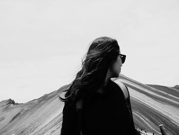 Young woman looking away against sky