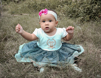 Portrait of cute baby girl sitting on land