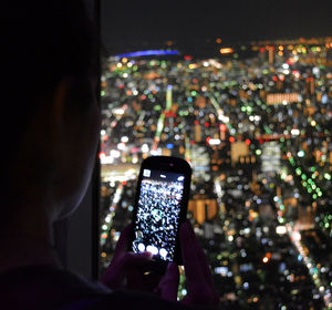 Man photographing illuminated cityscape at night