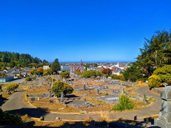 High angle view of townscape by sea against clear blue sky