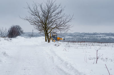 Yellow tractor cleans up snow from road. cleaning and cleaning of roads in city from snow in winter