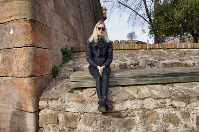 Portrait of woman sitting in stone wall