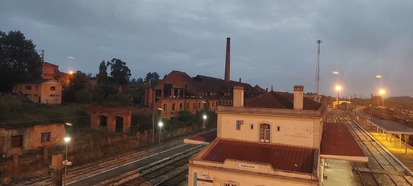 Illuminated buildings in city against sky at dusk