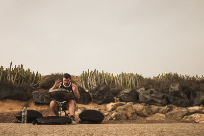 Man sitting on rock against clear sky