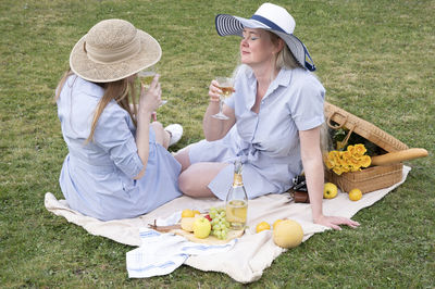 A two young women in a similar blue dress is resting on a picnic, chees plate