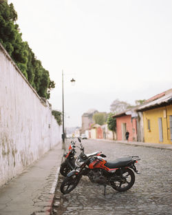 Bicycles on street by buildings against sky