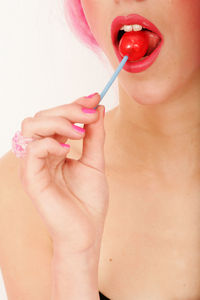 Midsection of woman eating lollipop against white background
