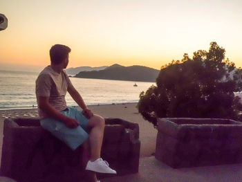 Woman sitting on beach looking at sunset