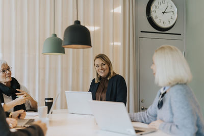 Smiling women using laptops in office