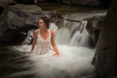 Full length of young woman looking at waterfall