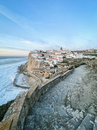 Buildings by sea against sky