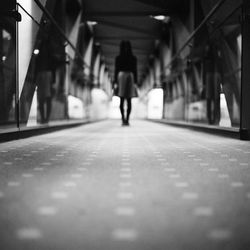 Rear view of man walking in illuminated corridor