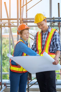 Coworkers with blueprint at construction site