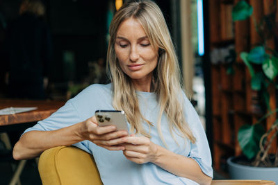 Young attractive blonde woman uses mobile phone to surf the internet.