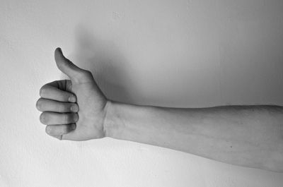 Cropped image of male hand gesturing good luck against wall