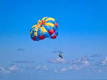 Low angle view of person paragliding against sky