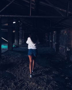 Rear view of woman walking in abandoned building