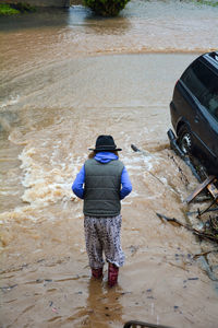 Rear view of girl standing on flooded road