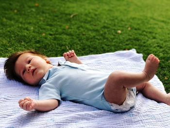 Baby lying on blanket on grass