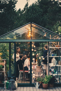 Happy young multi-ethnic group enjoying dinner party in conservatory at back yard