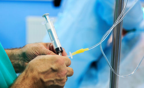 Close-up of doctor holding syringe and iv drip