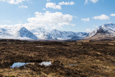 Snowcapped mountains against cloudy sky