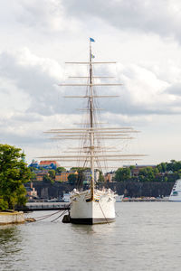 Sailboats moored at harbor against sky