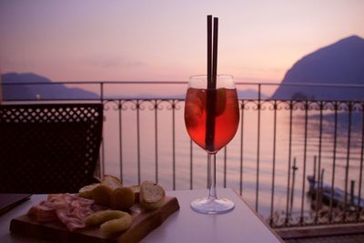 Close-up of beer on table against sea during sunset