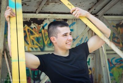  young man standing against graffiti wall