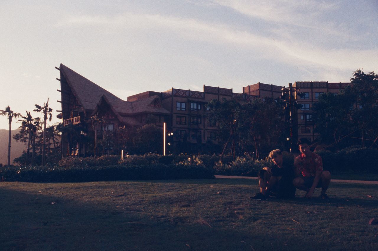 PEOPLE SITTING OUTSIDE BUILDINGS IN CITY AGAINST SKY