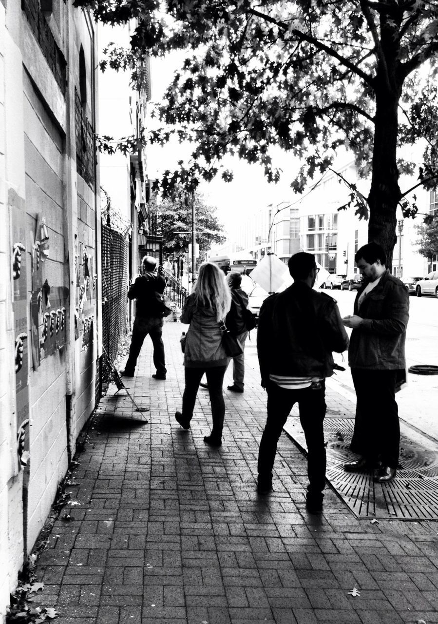 walking, rear view, men, building exterior, city, full length, person, lifestyles, architecture, built structure, street, the way forward, city life, sidewalk, footpath, leisure activity, cobblestone, tree