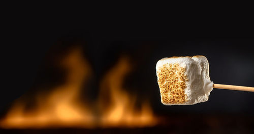 Close-up of hand holding burning wood against black background