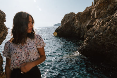 Beautiful young woman standing against sea