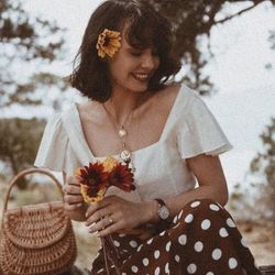 Happy woman holding flower while standing against plants