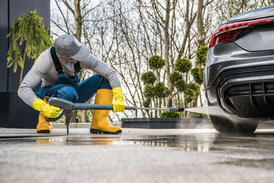 Mature man cleaning car on street